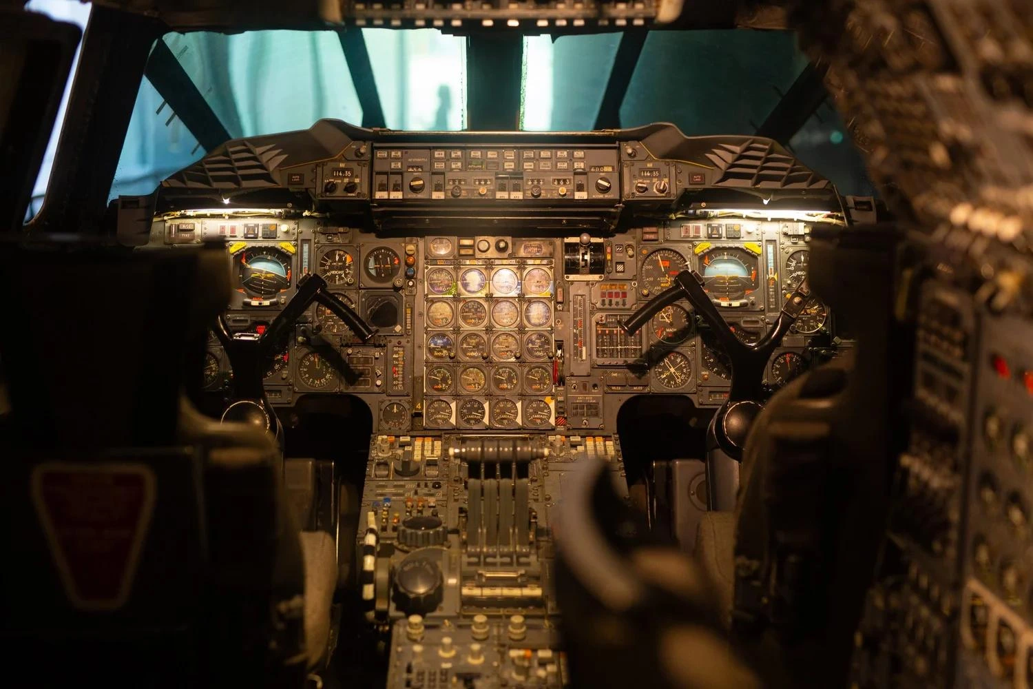 View inside an aircraft cockpit featuring two pilot control yokes and a detailed instrument panel filled with analogue gauges, switches and flight controls.