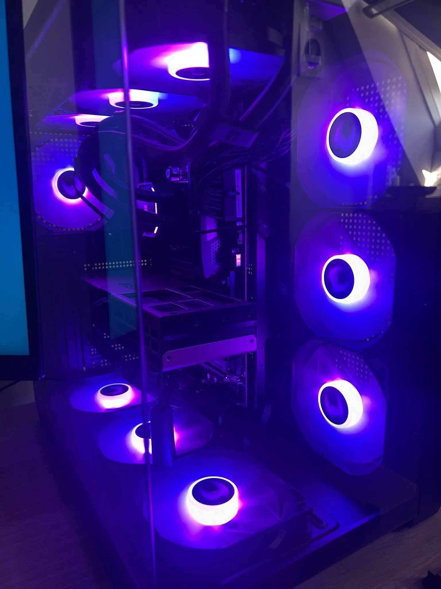 Close-up of a custom gaming PC with a glass case and multiple RGB cooling fans glowing purple and blue.